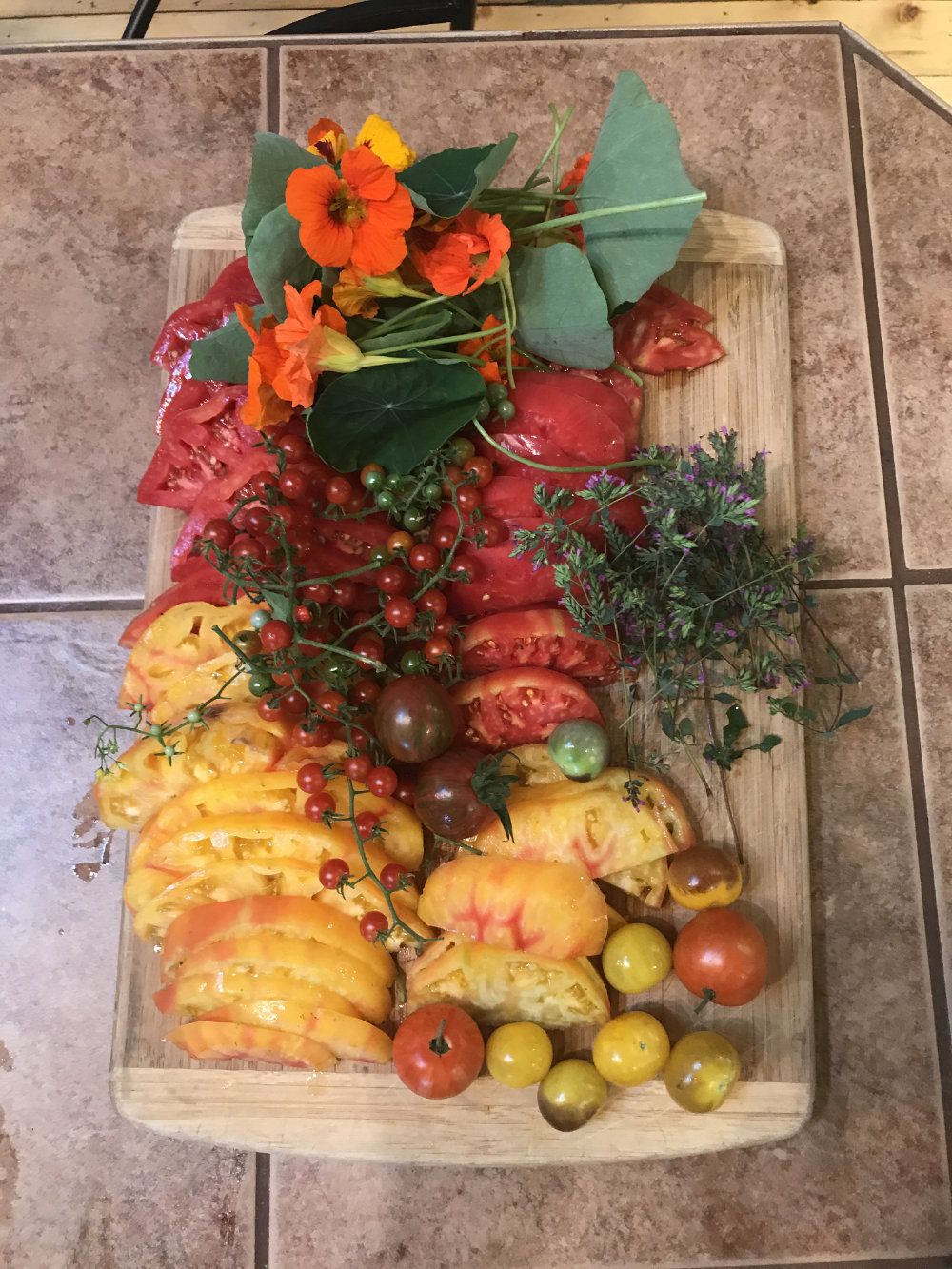 Gorgeous red, yellow, and orange colored home grown heirloom tomatoes are cut and served on a tray.