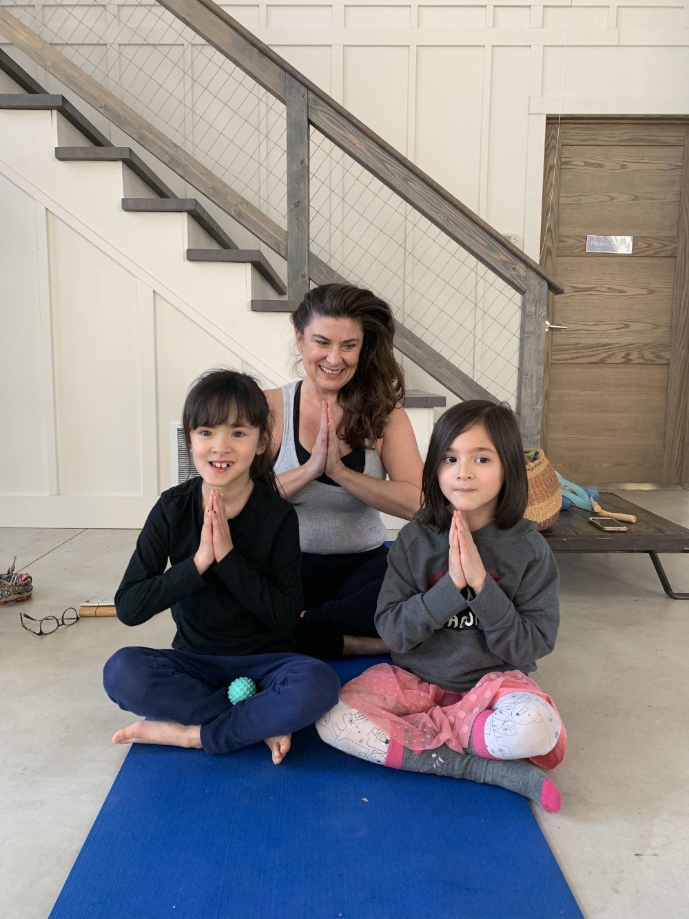 Two young girls and yoga instructor pose after yoga class.