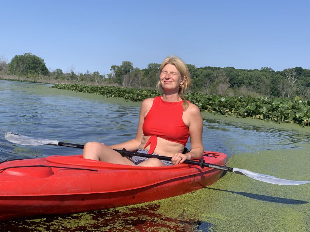 Julie smiles at the sun while kayaking in the marshland.