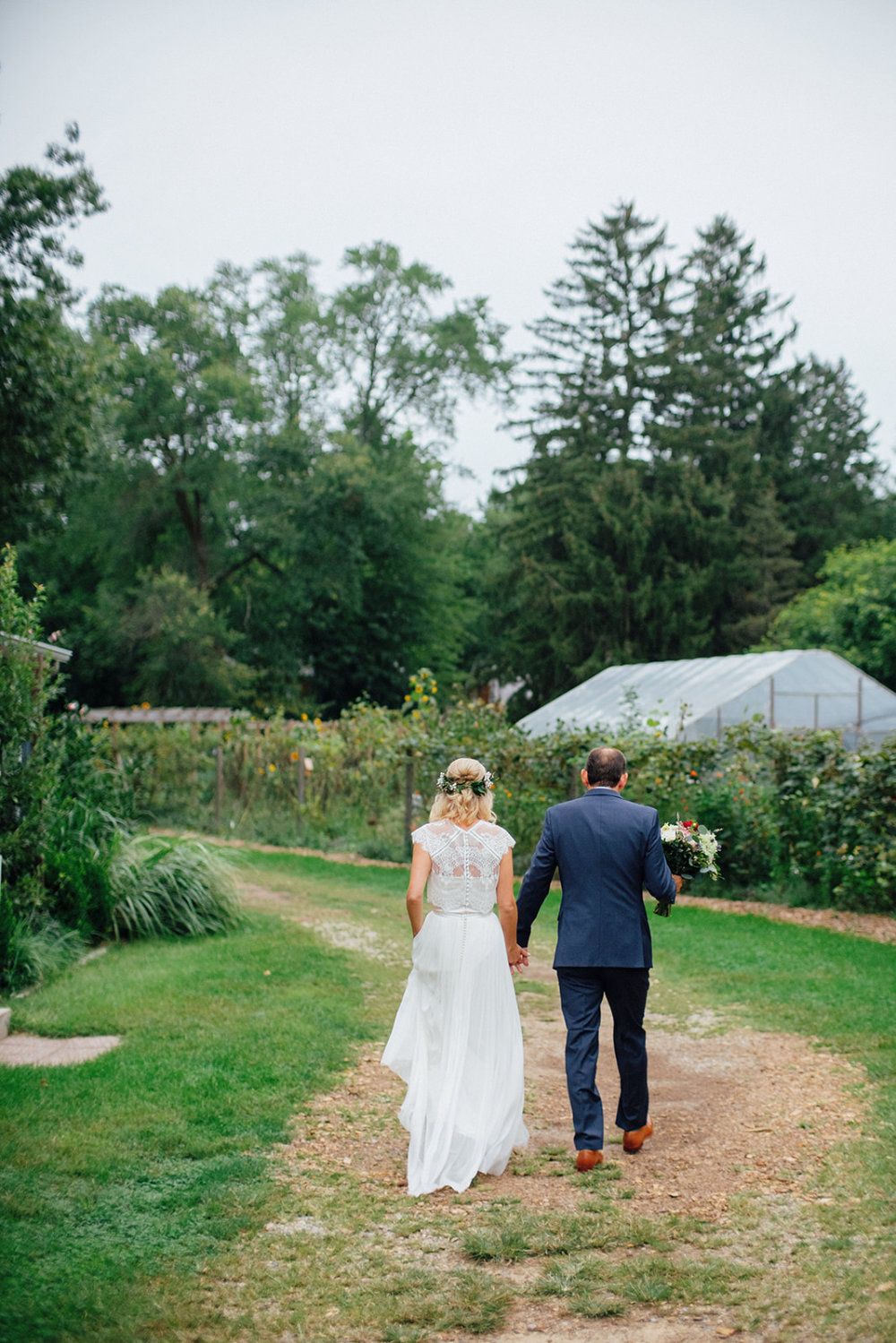 On their wedding day, a couple holds hands while walking past the gardens.