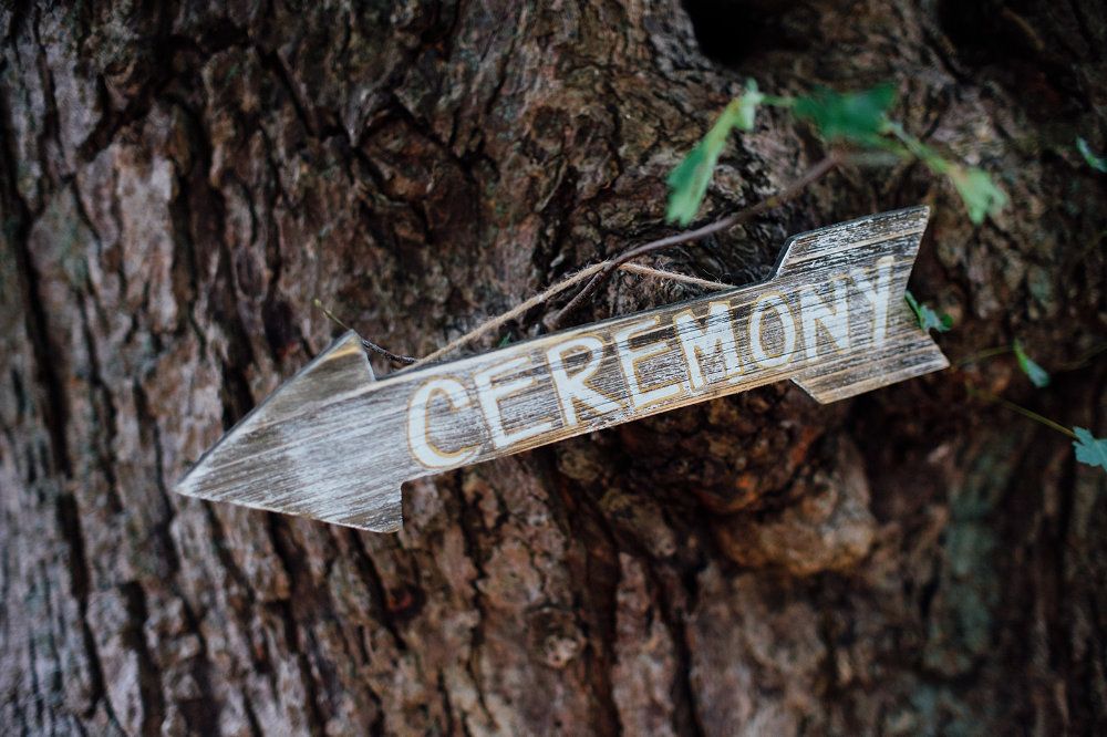 Hung on a tree, an arrow shaped sign reads "Ceremony."