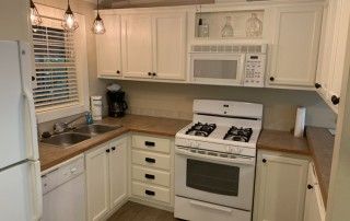 A direct view of the kitchen. This includes all full size kitchen appliances including a microwave, oven, dishwasher, fridge, sink, and coffee maker.