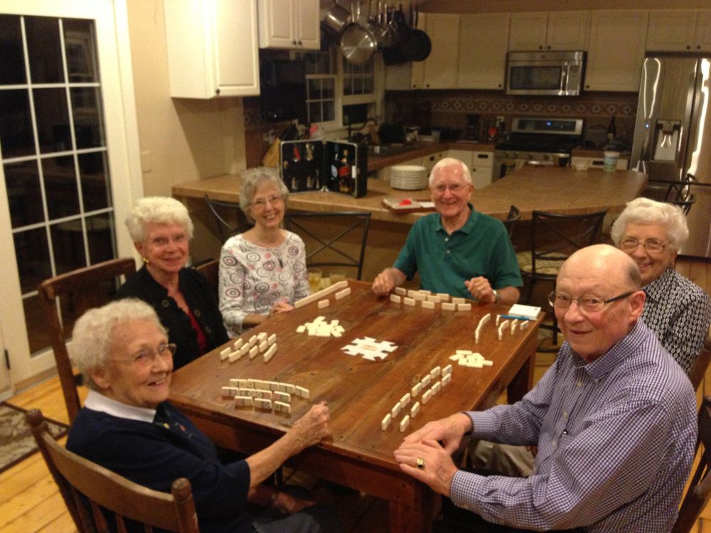 A group sits around the dining room table while playing a game.