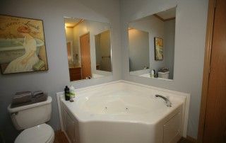 The primary bathroom includes a large jacuzzi and separate shower. Two mirrors reflect the whole bathroom.