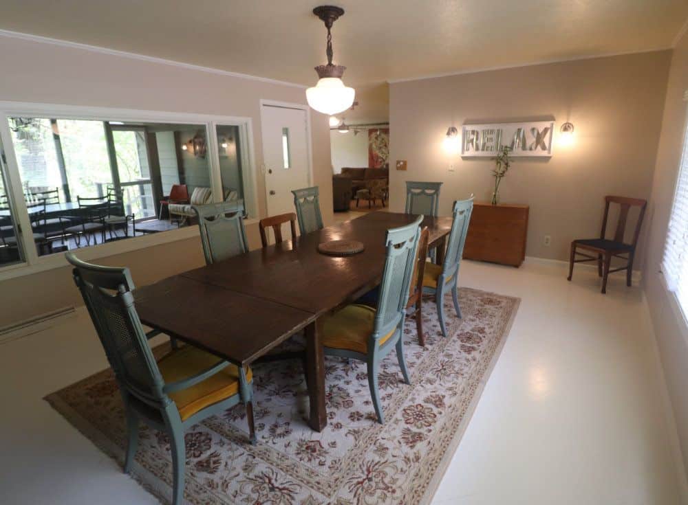 The spatial dining room includes a large dining table and chairs and is lit by natural light.