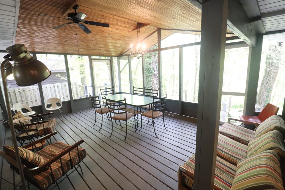 The spacious screen porch includes a table and chairs, comfortable lounge chairs, and a sofa.