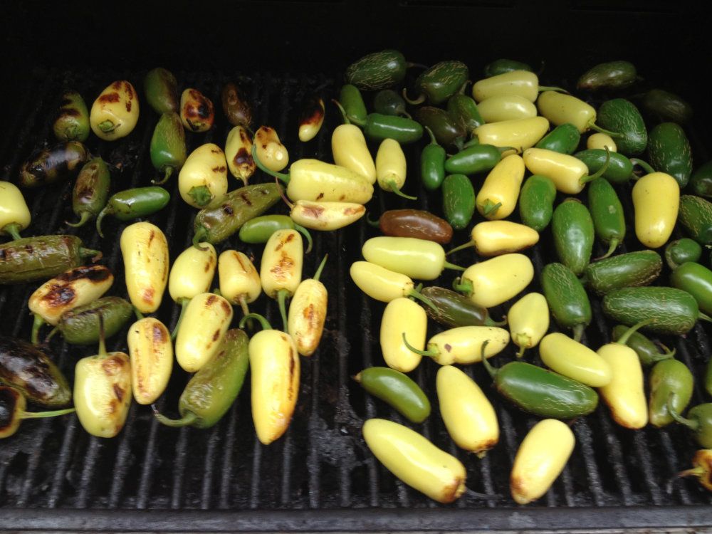 An assortment of peppers blacken on a grill.