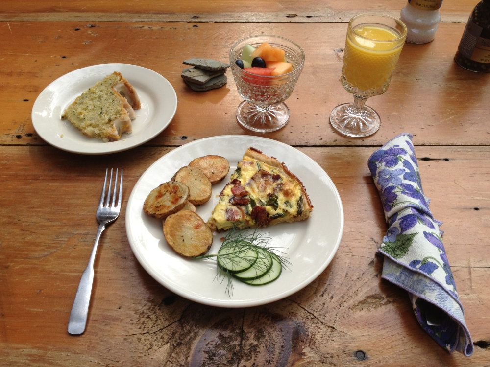 Bacon asparagus quiche, rosemary potatoes, fresh homme grown cucumber, a fruit cup, and lemon poppy seed cake paired with a glass of orange juice.