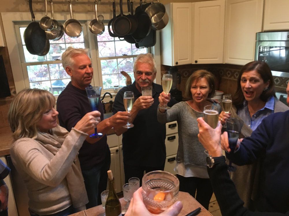 A group cheers glasses in celebration in the kitchen of The Inn.