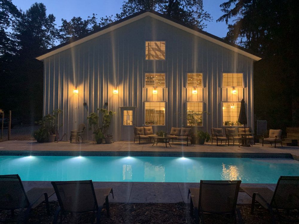 The barn lights shine gracefully over the pool at nighttime.