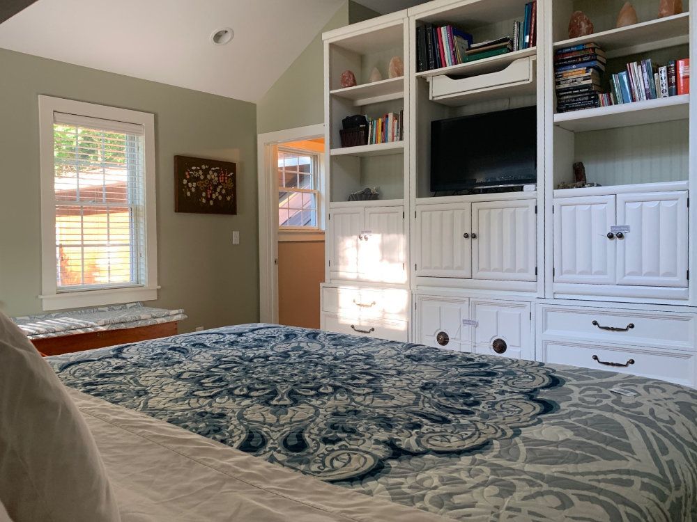 The Primary bedroom shows a king sized bed, a bench, and bookshelves.