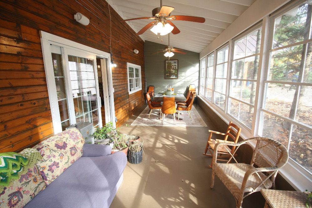 The screen porch includes a seating area that consists of a pull-out couch, a side table, and a few chairs. In the background, the seating area can be seen.