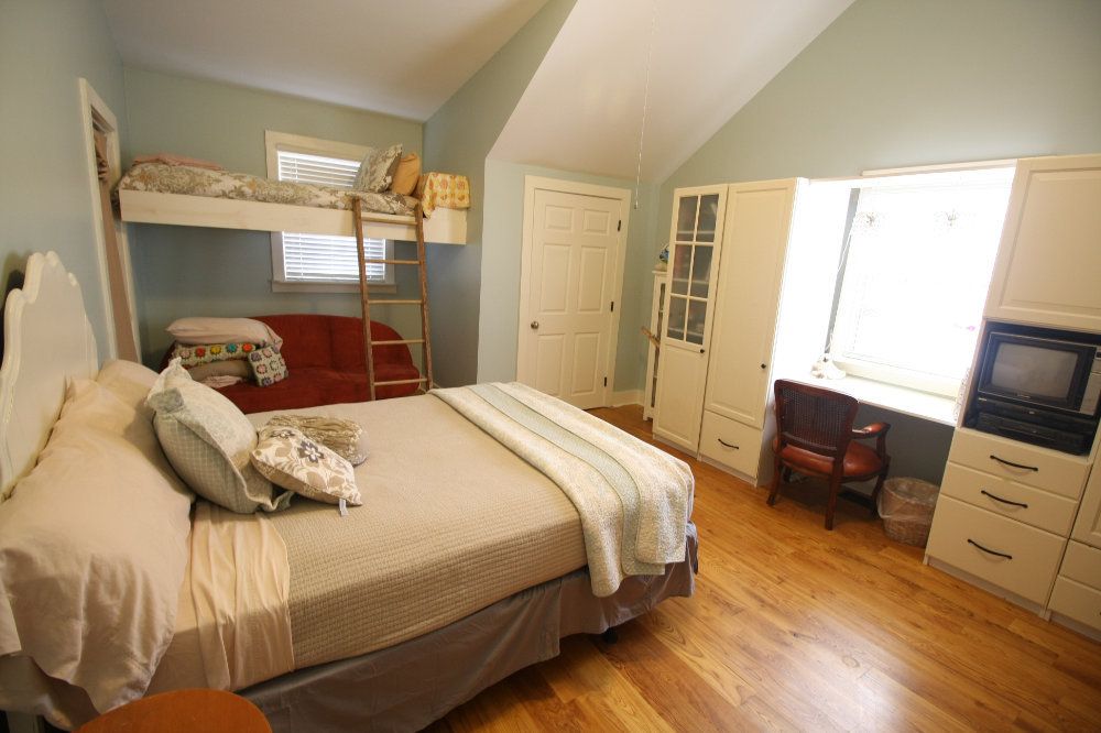 This bedroom includes a queen sized bed, a lofted twin sized bed over the fold-flat couch, and cabinets/desk.