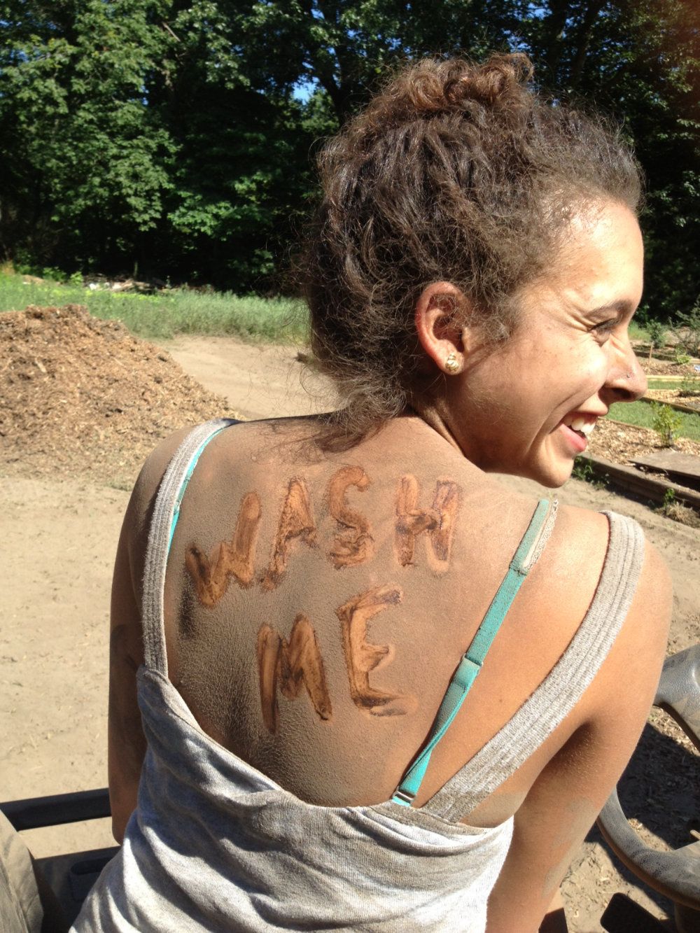 Our first summer intern, Emily, covered in dirt with the words "Wash Me" written on her back.