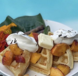 Crispy, fluffy yeasted waffles topped with ripe, chopped peaches, butter and fresh whipped cream.