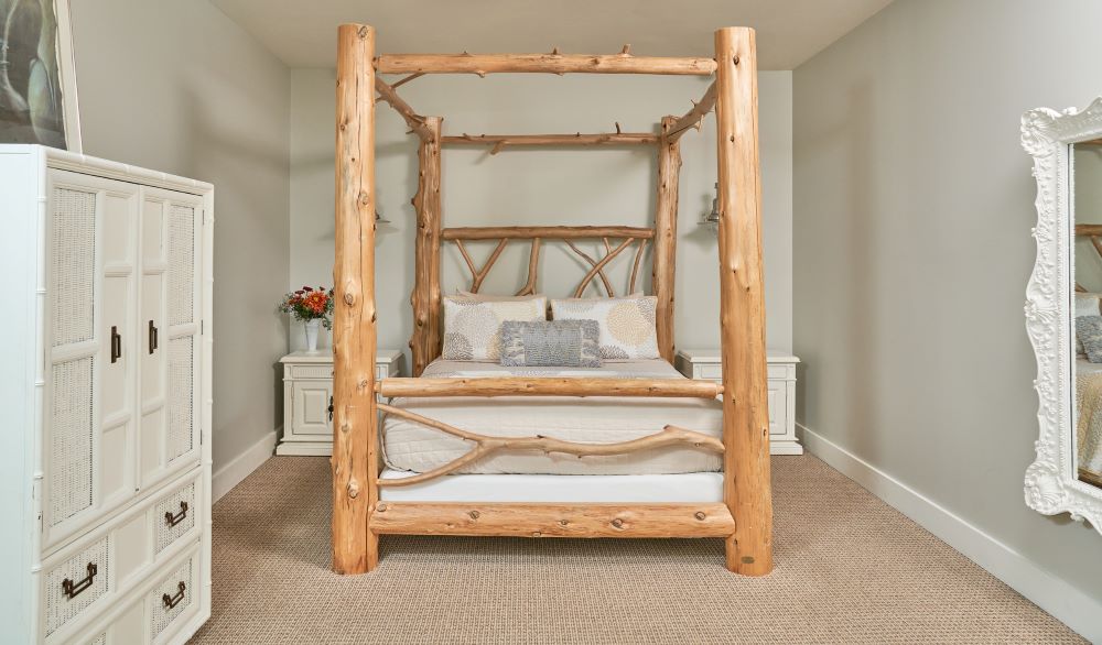 Cedar Log's Bedroom has a tall cedar bedframe paired with white nightstands, dressers, and a full length mirror in this image.