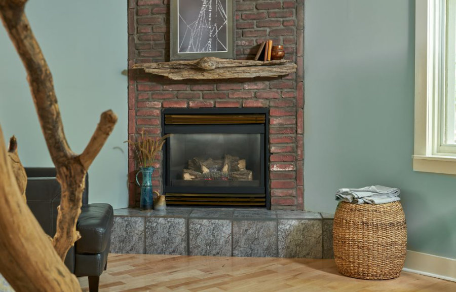 Driftwood's brick gas fireplace with driftwood mantle and nearby leather chair and ottoman.