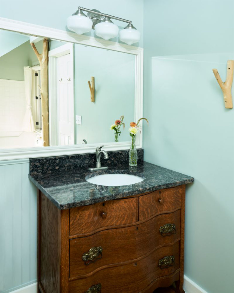 Golden Maple's bathroom featuring antique dresser with stone countertop sink, decorated with flower bouquet.