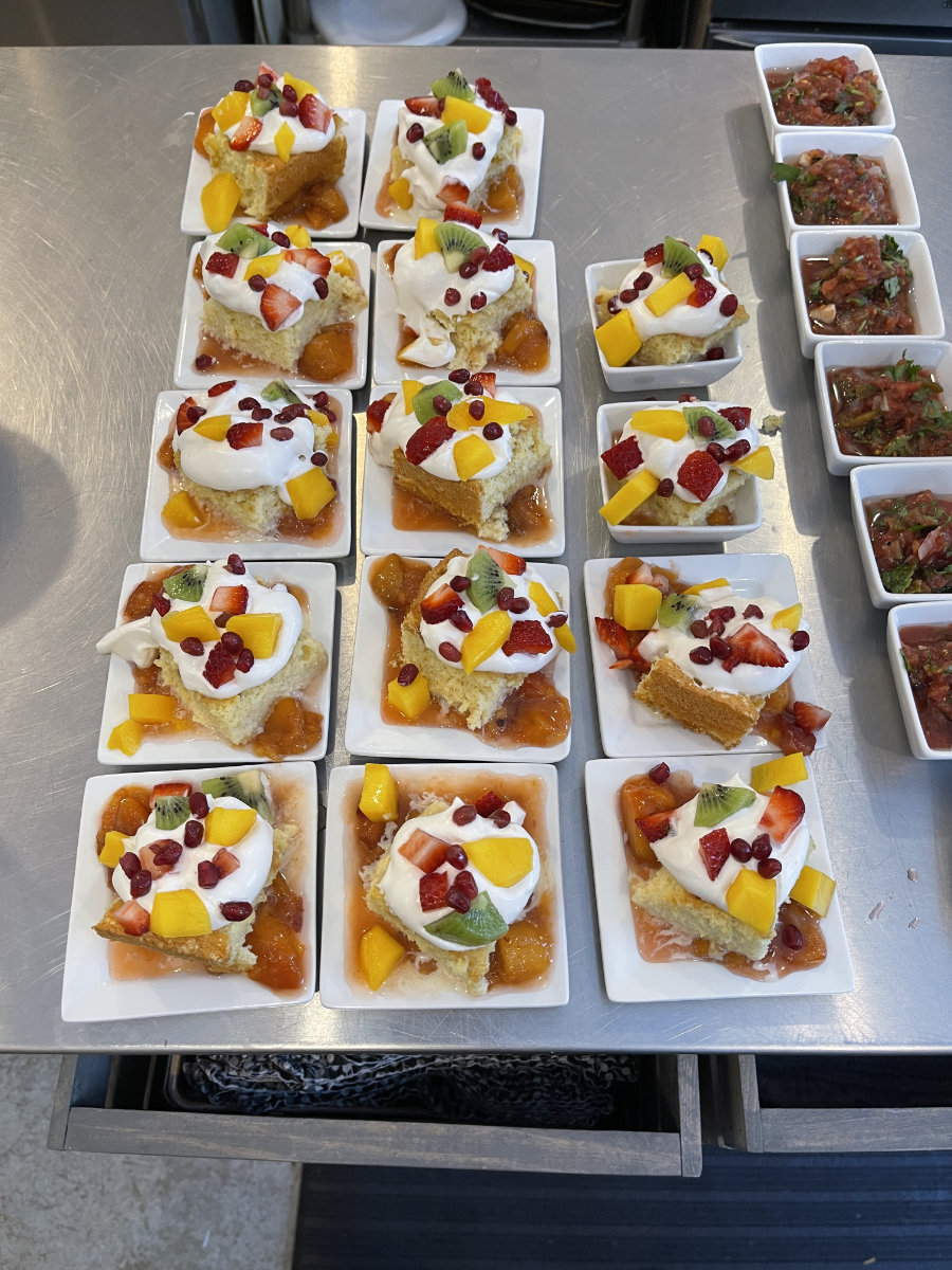 Individually sliced Tres Leches cake topped with whipped cream, mango, kiwi, pomegranate, and raspberries.