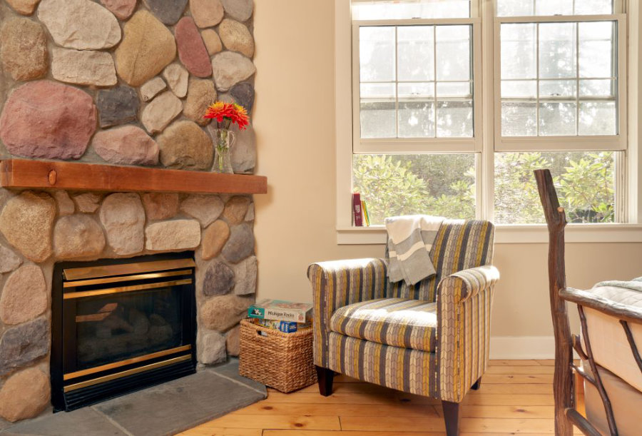 Ironwood's stone fireplace with comfy chair to relax in by sun-filled windows
