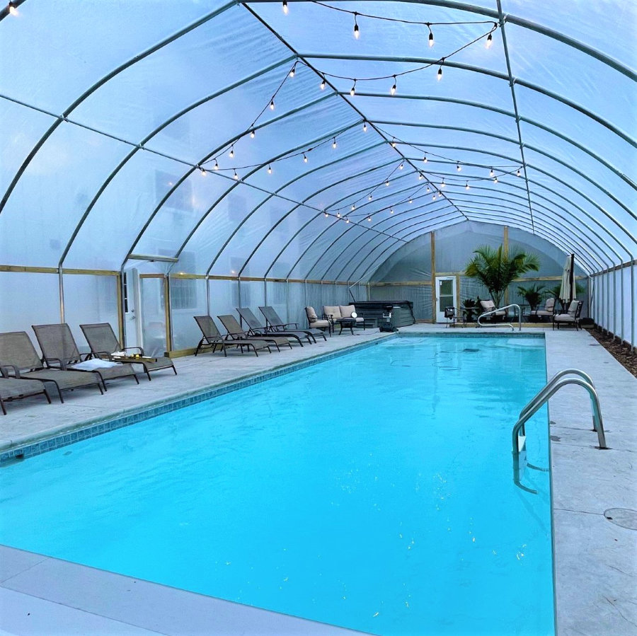 A view of the heated pool inside the enclosure with plenty of chaise lounges beside it.