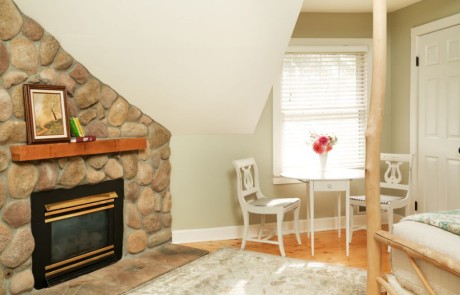 Silver Maple bedroom with stone fireplace and table and chairs