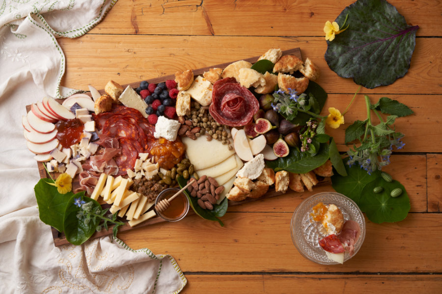 Charcuterie platter with multiple meats and cheeses along with homemade jams and mustard
