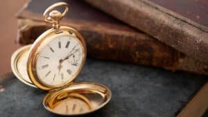 vintage gold pocket watch next to a few leatherbound books