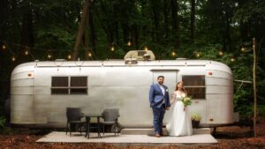 bride and groom standing in front of one of the vintage campers at goldberry woods