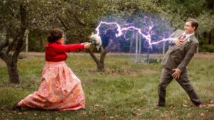 bride using bouquet to strike lightning at her groom while standing in the orchards at goldberry woods