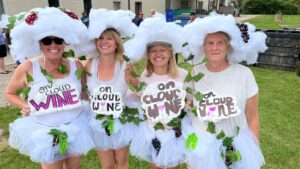 goldberry woods innkeeper julie with three friends ready to go grape stomping dressed in costumes and holding signs reading on cloud wine