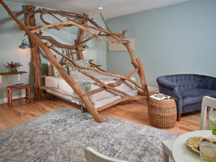 A guestroom painted in a soft blue. with a stunning bed made from enormous driftwood logs from a lake.