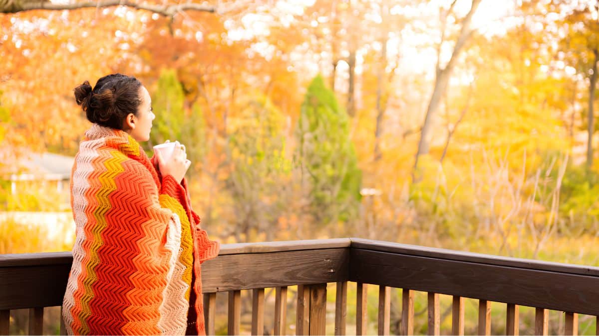 Woman drinking coffee on a fall morning on a balcony at Goldberry Woods