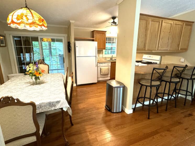 An open kitchen, dining room, and breakfast bar with 3 barstools.