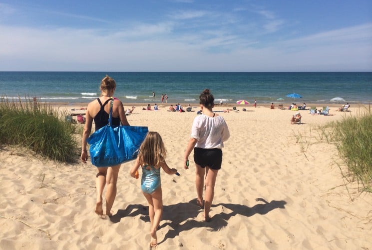 A family of three walking in the sand towards the lakeshore