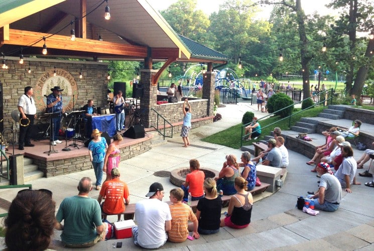 A group of people gathered at an outdoor amphitheater with a band playing on a small stage