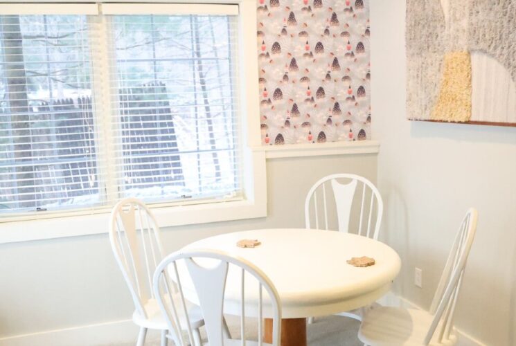 Breakfast nook with a white table and four chairs by a large window