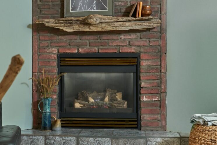 Leather chair by a gas fireplace with brick detail and driftwood mantle