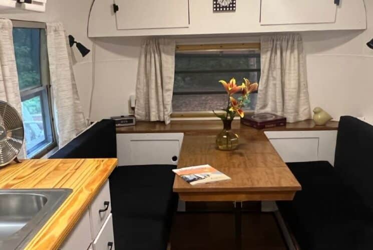 Black bench seats and table in a camper with sink and wood countertop