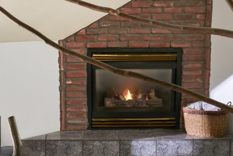 Black leather chair next to a cozy gas fireplace with brick detai