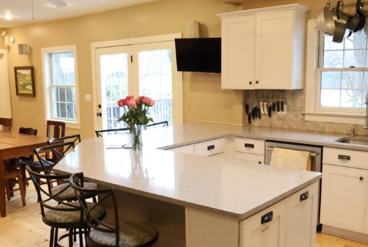 Kitchen of a home with white cabinets, grey countertop, dining area and large bright windows
