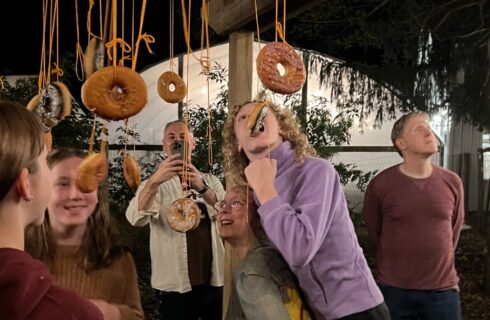 A group of people trying to eat donuts hanging from strings