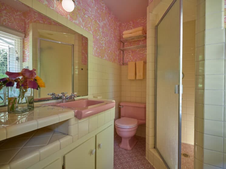 A vintage bathroom in pinks and light greens with a corner shower.