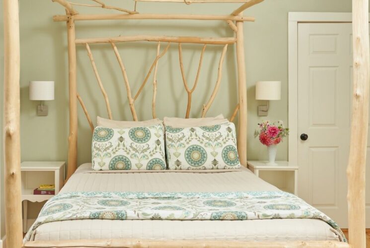 A custom silver maple artisan-made bed with a patterned quilt and pillows and two side tables