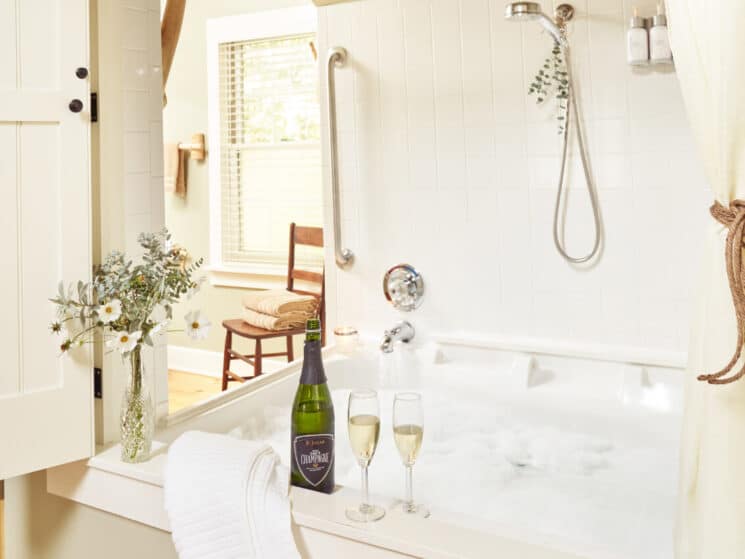Large Jacuzzi tub with champagne bottle, two glasses of champagne and vase of flowers