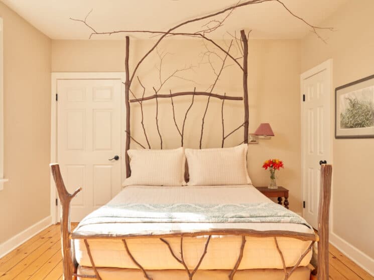 Bright and cozy bedroom featuring knotty pine floors, and a bed frame made of ironwood