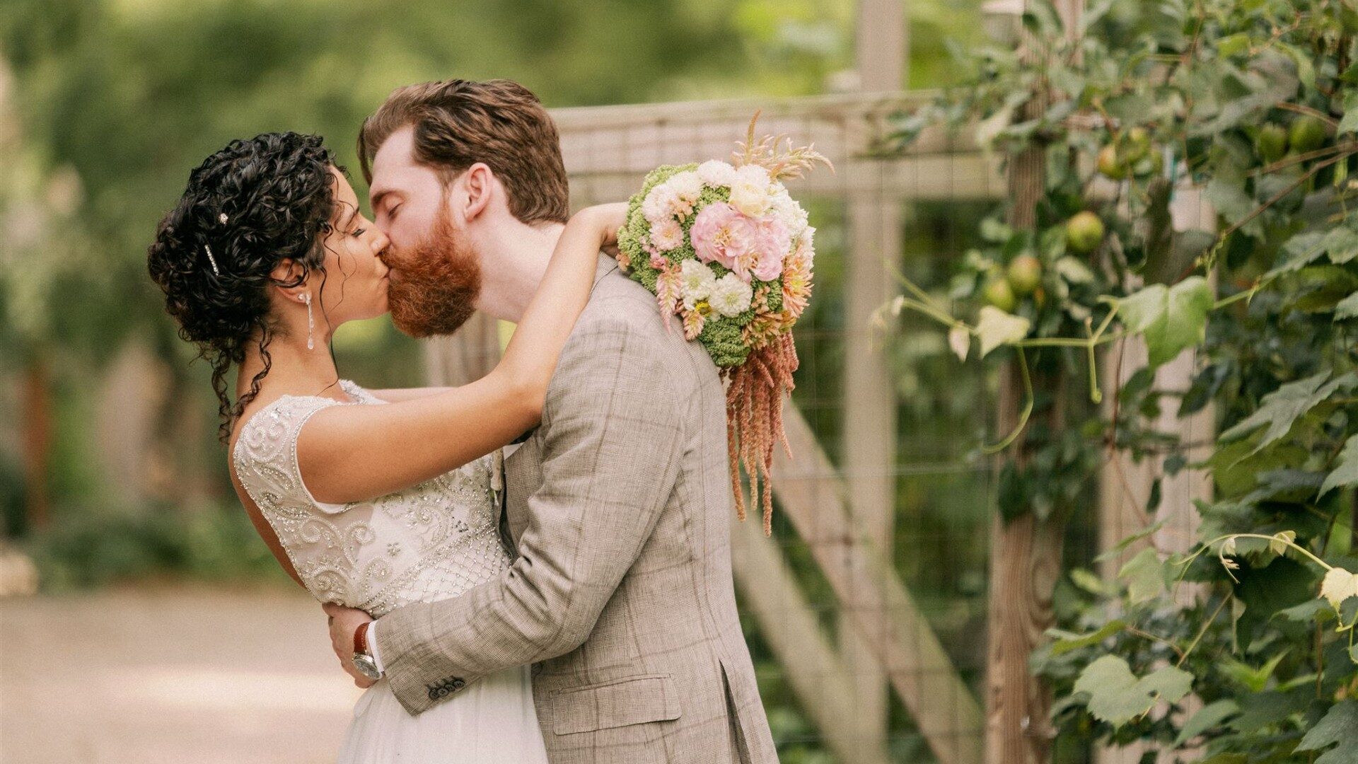 A bride and groom kissing in an outdoor garden