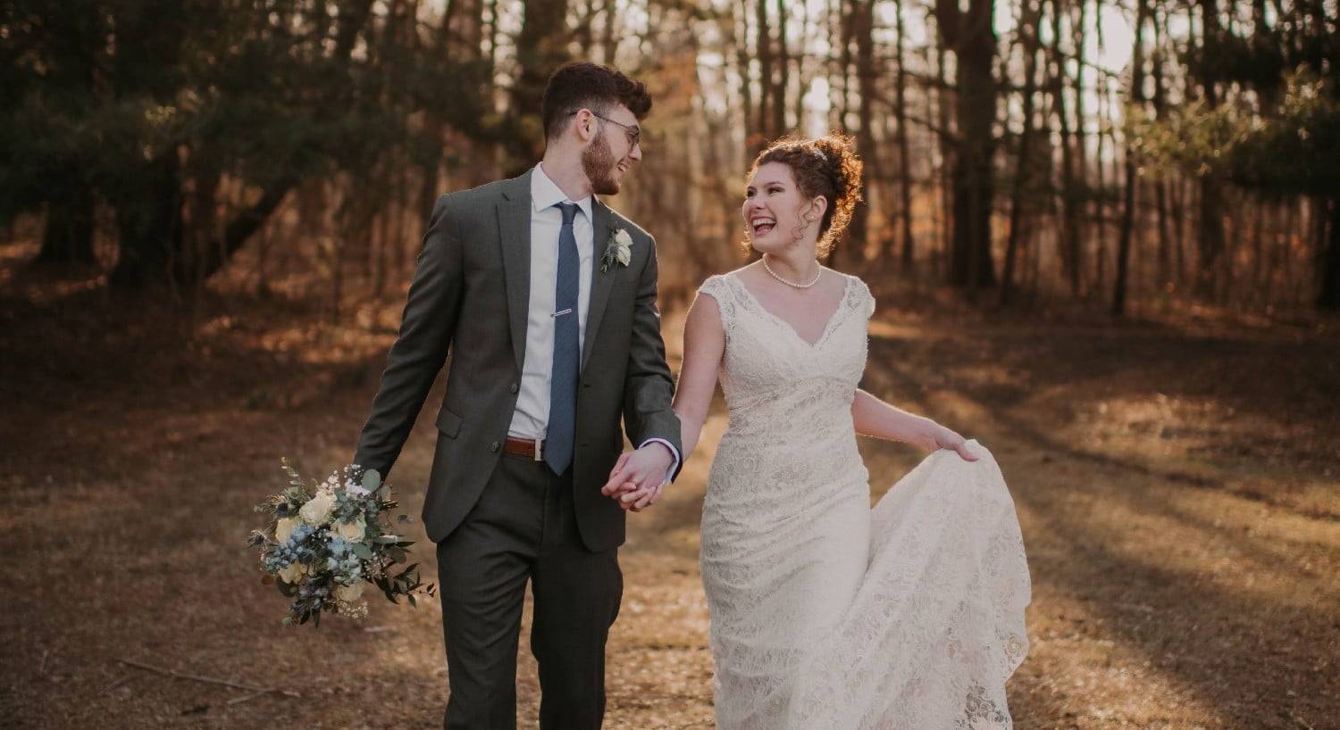 A bride and groom smiling and laughing together during a walk in the woods