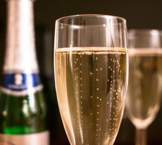 Two flutes of champagne next to an empty bottle