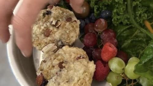 Hand placing Rhubarb Muffins into Room Service Basket garnished with kale, grapes, and raspberries from our farm